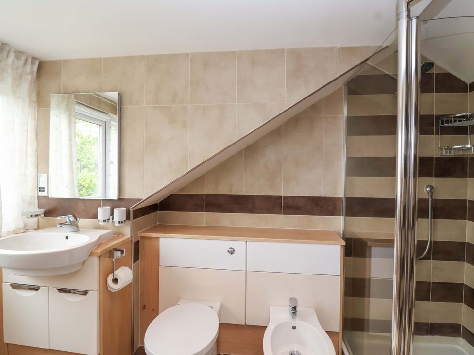 A bathroom with a sink, toilet, bidet, and shower at 26 Five Bells in Watchet