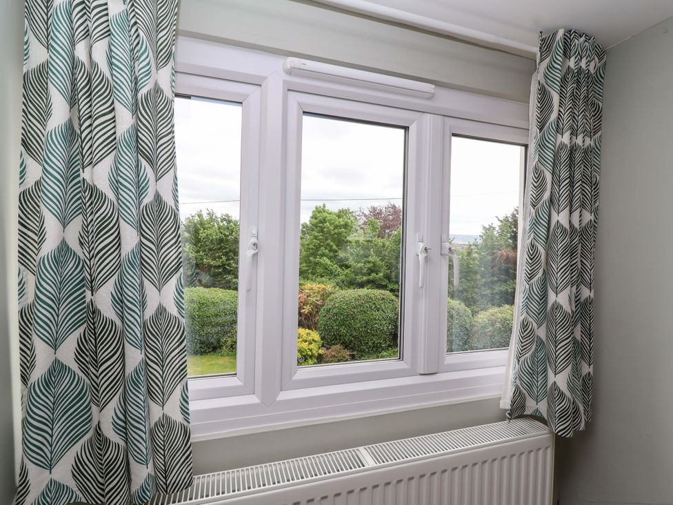 A window with patterned curtains and a radiator at 26 Five Bells in Watchet
