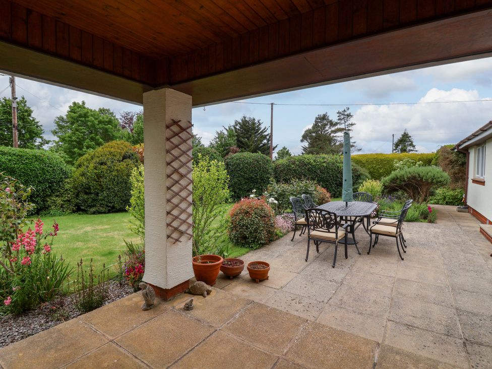 An outdoor patio with a table and chairs surrounded by a garden at 26 Five Bells in Watchet