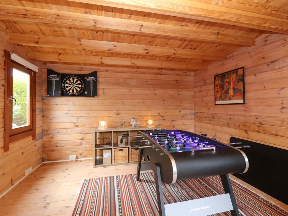 A games room with a foosball table and a dartboard at 26 Five Bells in Watchet
