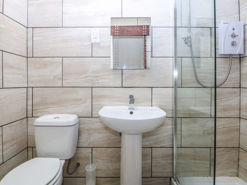 A bathroom featuring a toilet, sink, mirror, and shower at Seaview in Y Felinheli