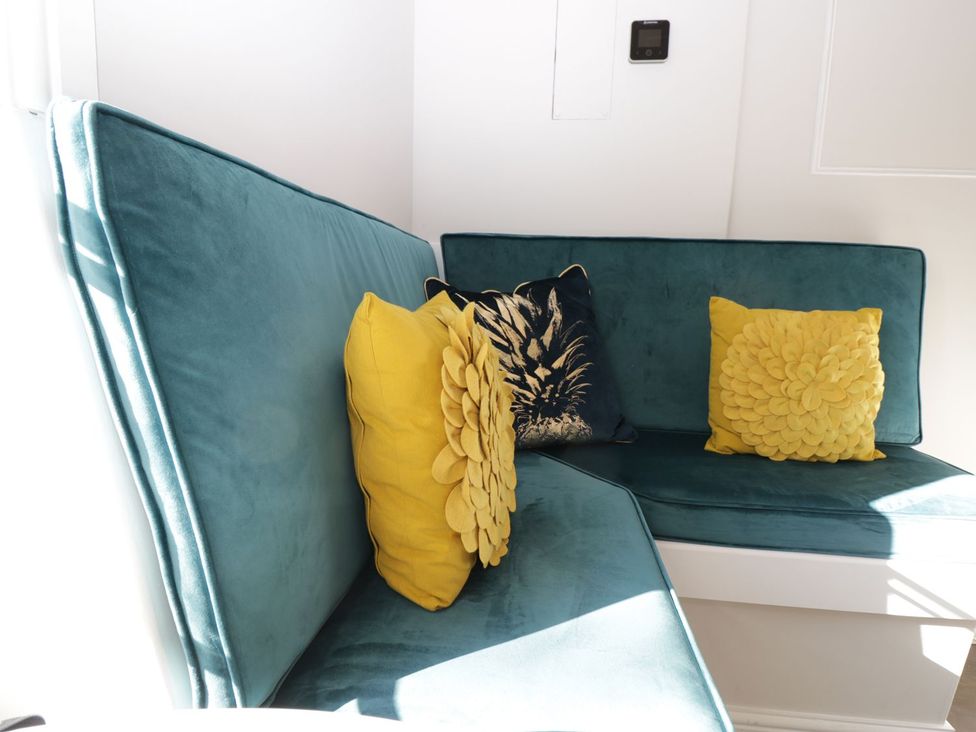 A snug with a teal couch and yellow pillows at Hamilton's Studio in Ryde