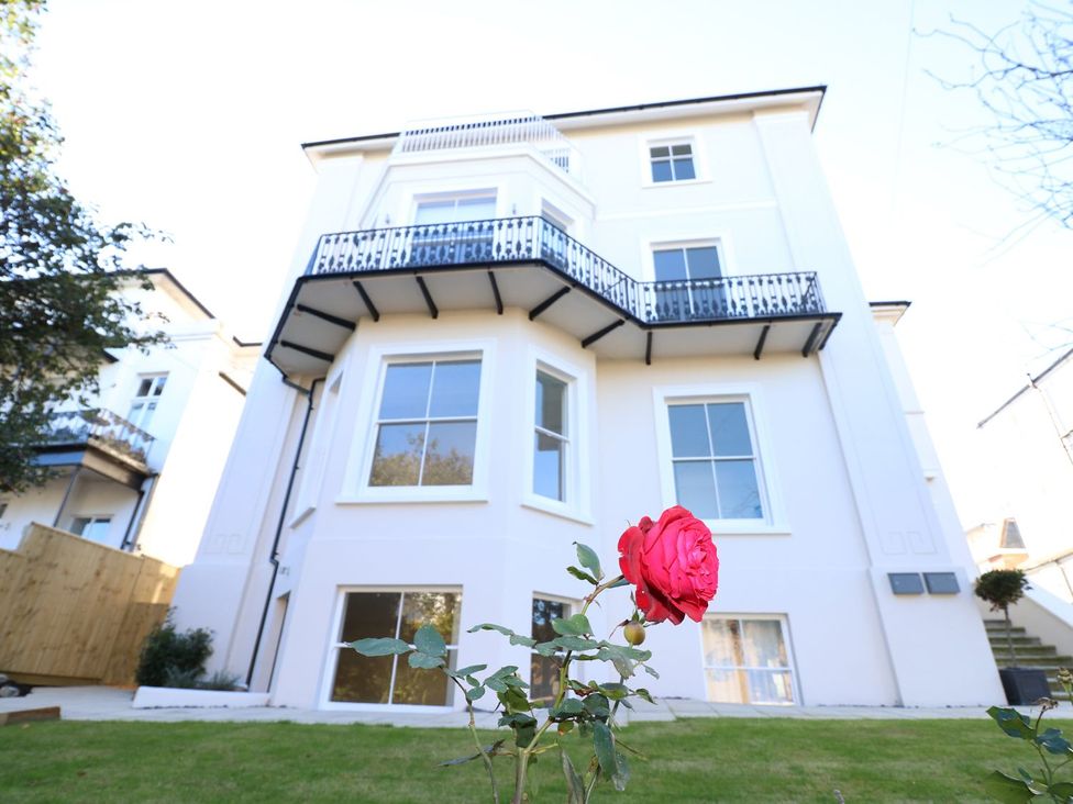 A house with a balcony and a rose in the garden at Hamilton's Studio Ryde