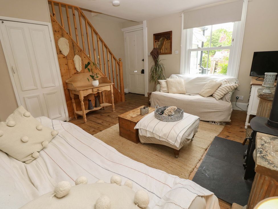 A living room with a sofa, coffee table, and staircase at Fern Cottage in Bembridge