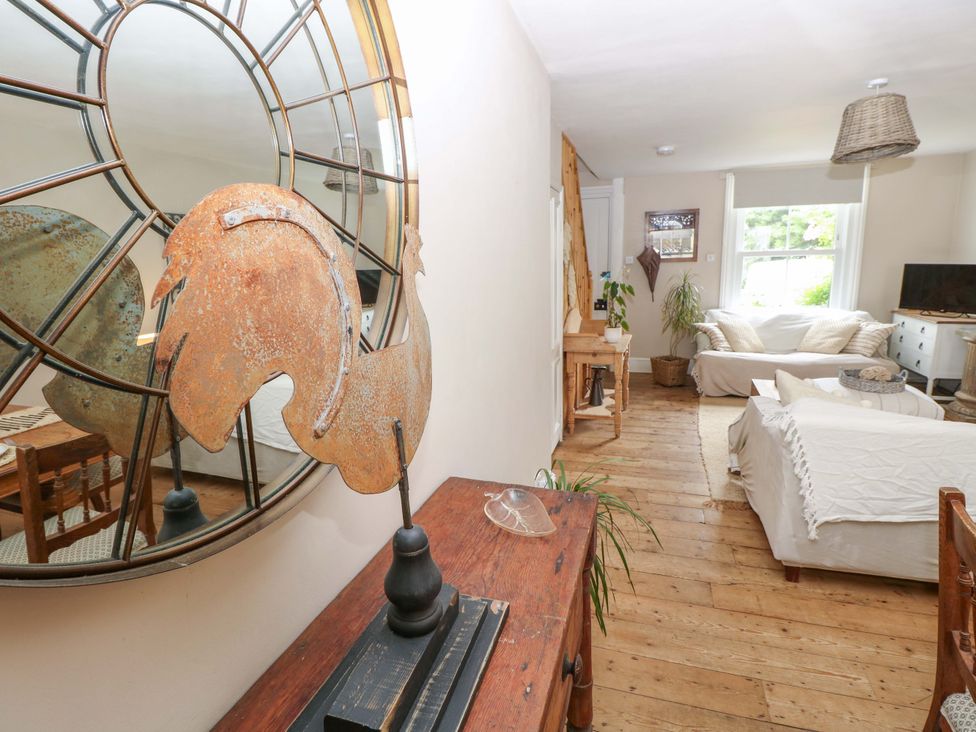 A living room with a mirror, sofa, and television at Fern Cottage in Bembridge