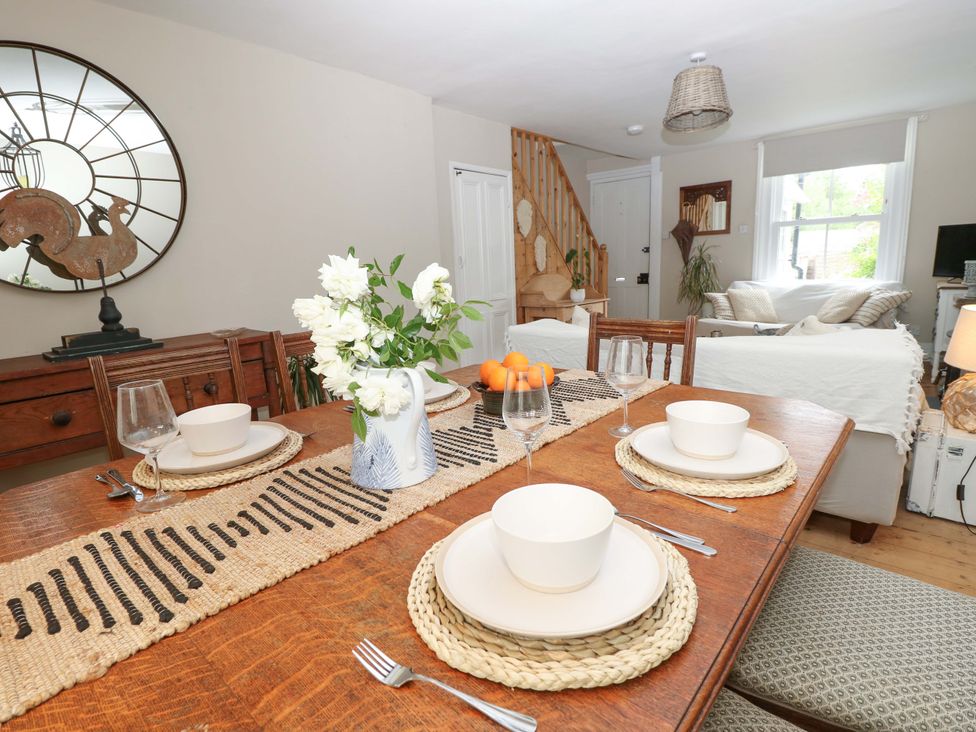 A dining room with a wooden table set and a mirror at Fern Cottage in Bembridge