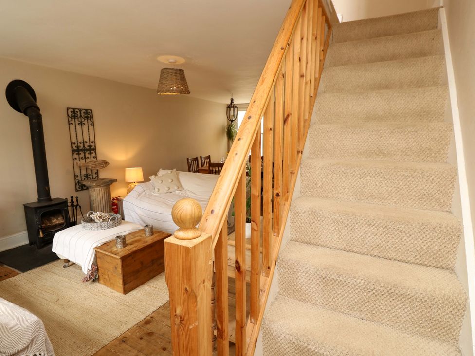 A living room with a staircase and wood stove at Fern Cottage in Bembridge
