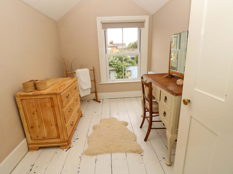 A bedroom with furniture including a chest of drawers and a vanity desk at Fern Cottage in Bembridge
