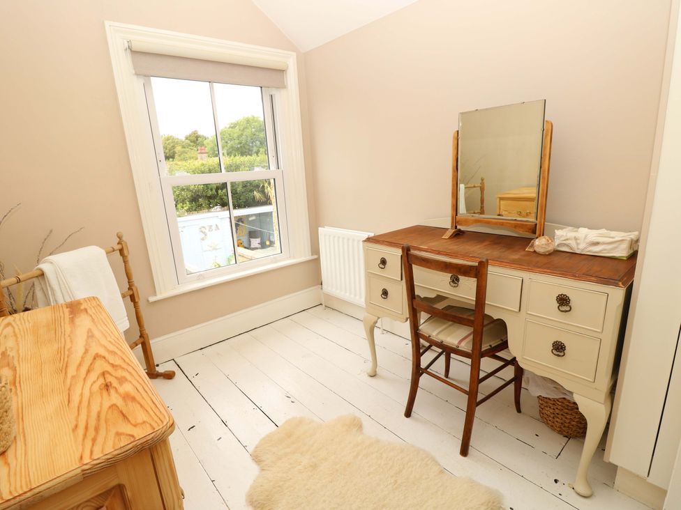 A bedroom with a desk and mirror at Fern Cottage in Bembridge