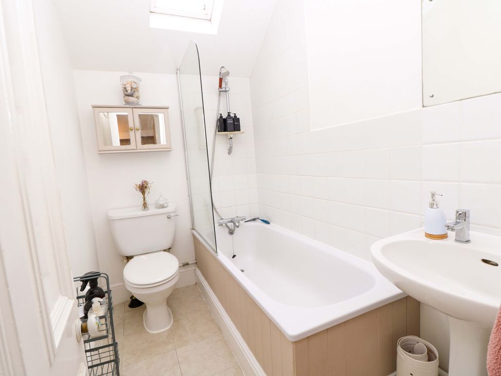 A bathroom with a tub, toilet and sink at Fern Cottage in Bembridge