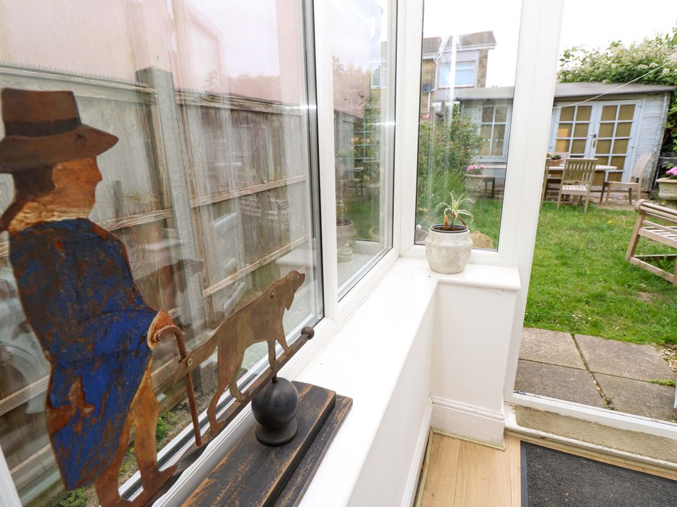 A conservatory with a figurine and view of the garden at Fern Cottage in Bembridge