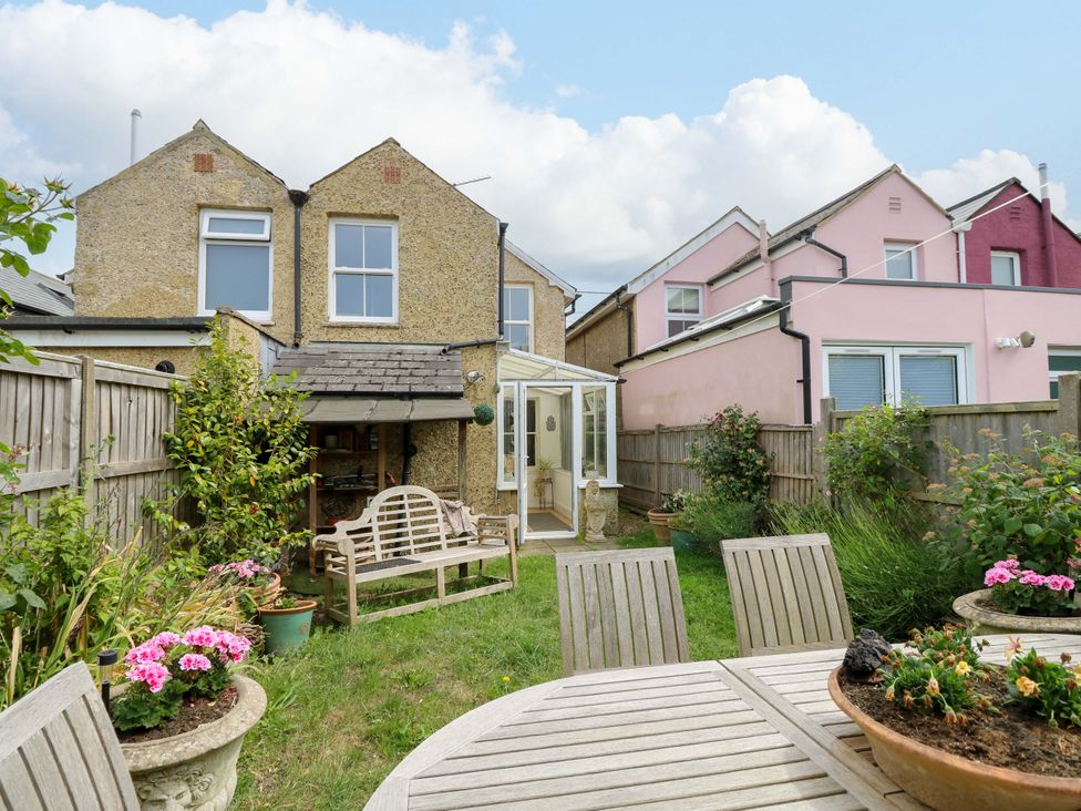 A garden with a bench and dining table at Fern Cottage in Bembridge