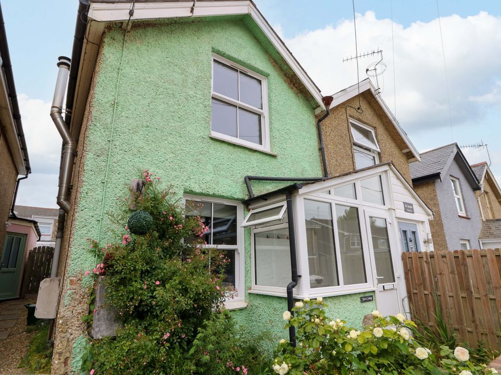 A house with green exterior and a conservatory at Fern Cottage in Bembridge