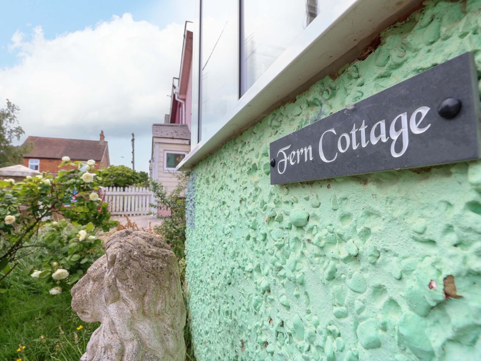 A sign for Fern Cottage with a stone lion in the garden at Fern Cottage in Bembridge