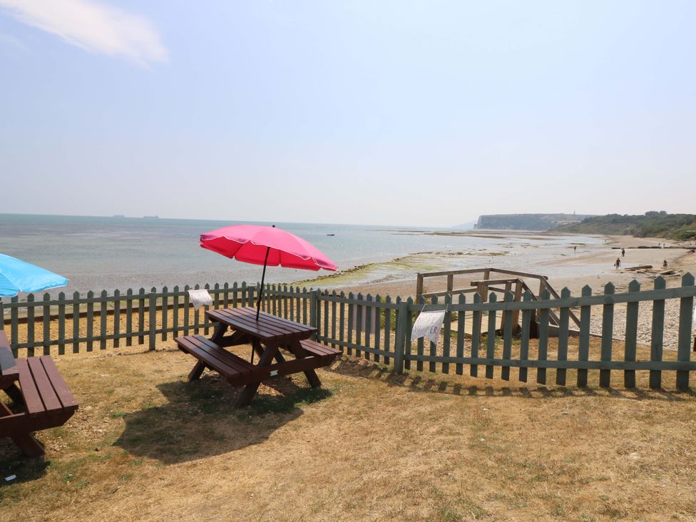 A beach area with picnic tables and umbrellas at Fern Cottage in Bembridge