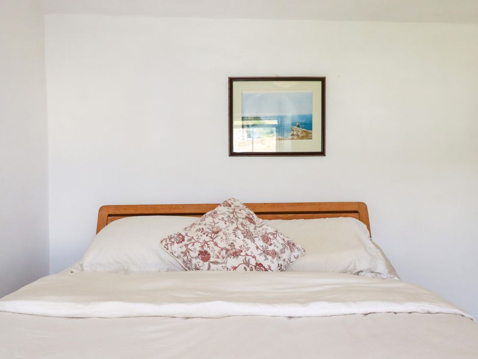 A bed with pillows and a picture on the wall at 18 Tregea Terrace in Portreath