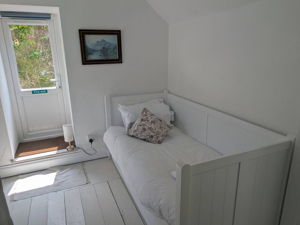 A bedroom with a bed and a door leading outside at Fairsands in Portreath
