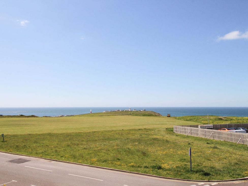 A view of the ocean and hill from a road at Portland View Portland Bill