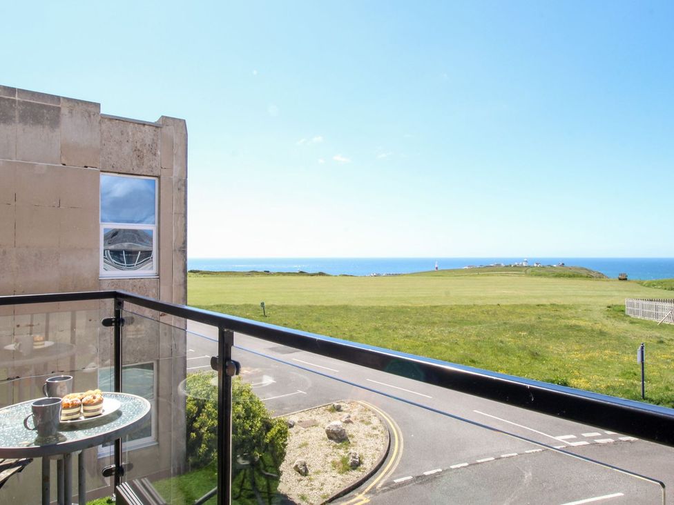 A balcony with table and cups overlooking the sea at Portland View in Portland Bill