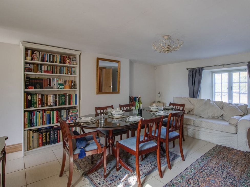 A dining room with a table and bookshelf at Honeypot Cottage in Weymouth