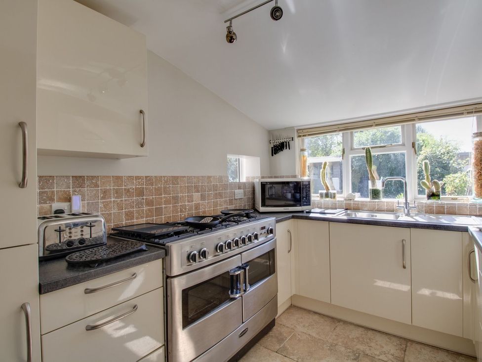 A kitchen with an oven, toaster and microwave at Honeypot Cottage in Weymouth
