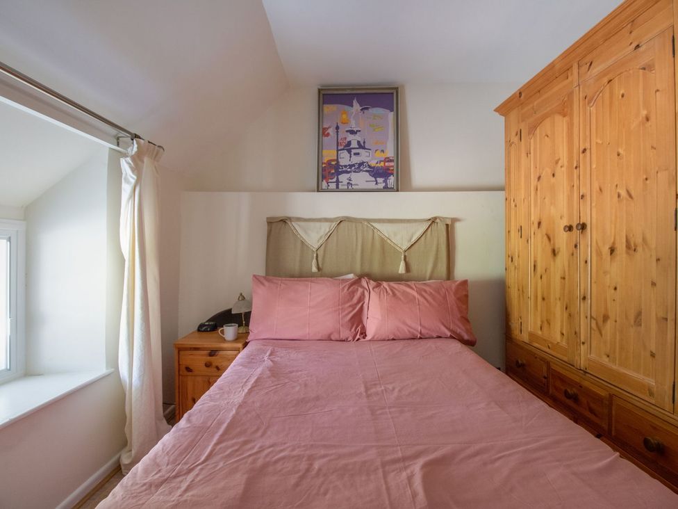 A bedroom with a bed and wardrobe at Honeypot Cottage Weymouth