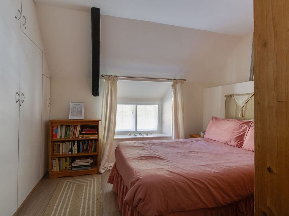 A bedroom with a bed and bookshelf at Honeypot Cottage in Weymouth