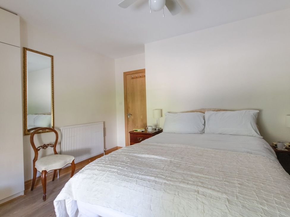 A bedroom with a bed and mirror at Honeypot Cottage in Weymouth
