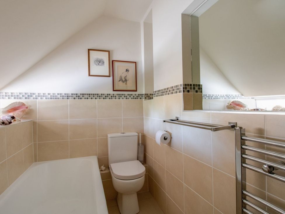 A bathroom with a bathtub and toilet at Honeypot Cottage in Weymouth