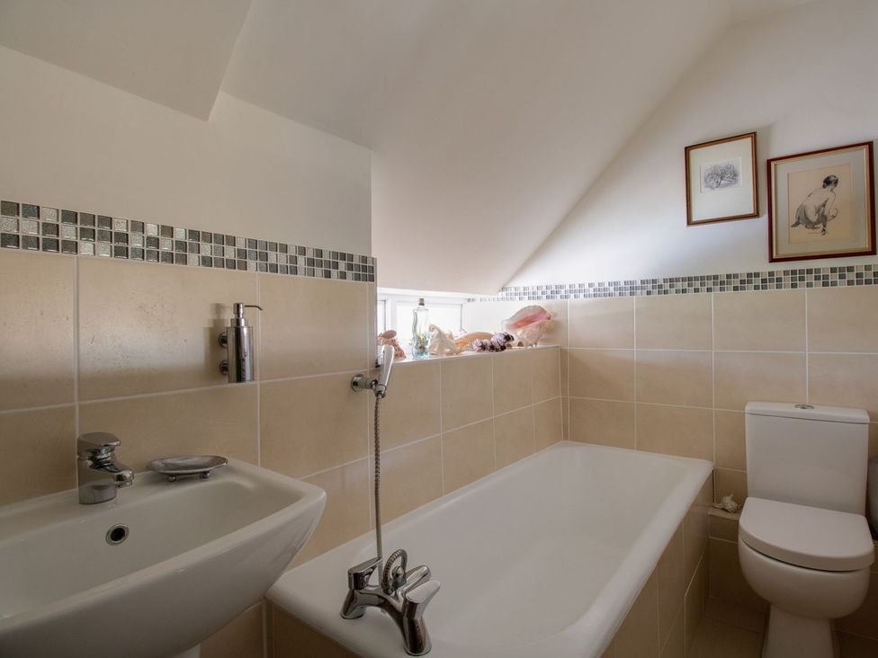 A bathroom with a bath tub and sink at Honeypot Cottage in Weymouth
