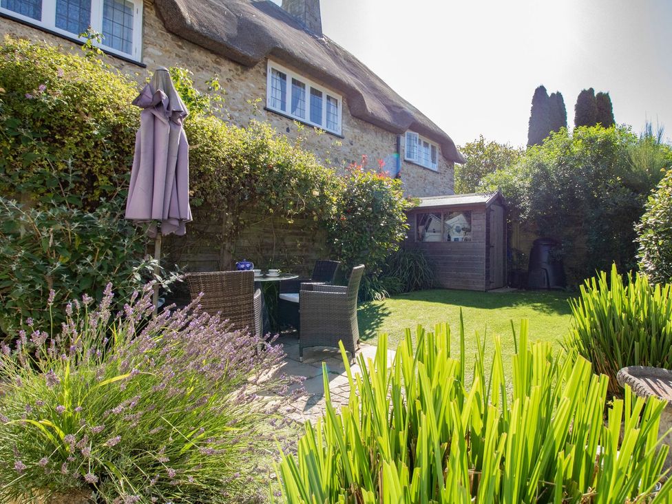 A garden with seating area and shed at Honeypot Cottage in Weymouth