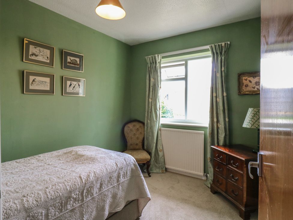 A bedroom with a bed, chair, table, and window at The Lodge 