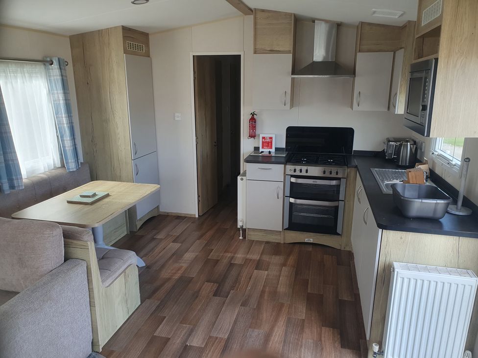 A kitchen and dining area with appliances and seating at Caravan 325 in Lowestoft