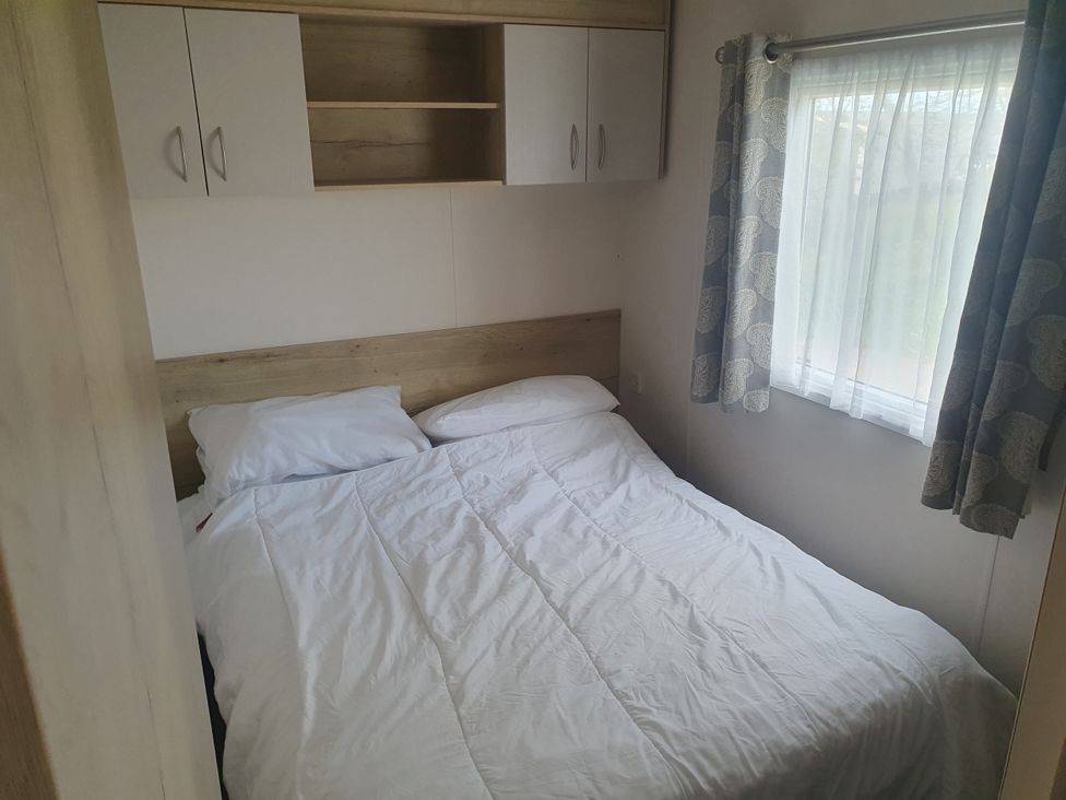 A bedroom with a bed and shelves at Caravan 325 in Lowestoft