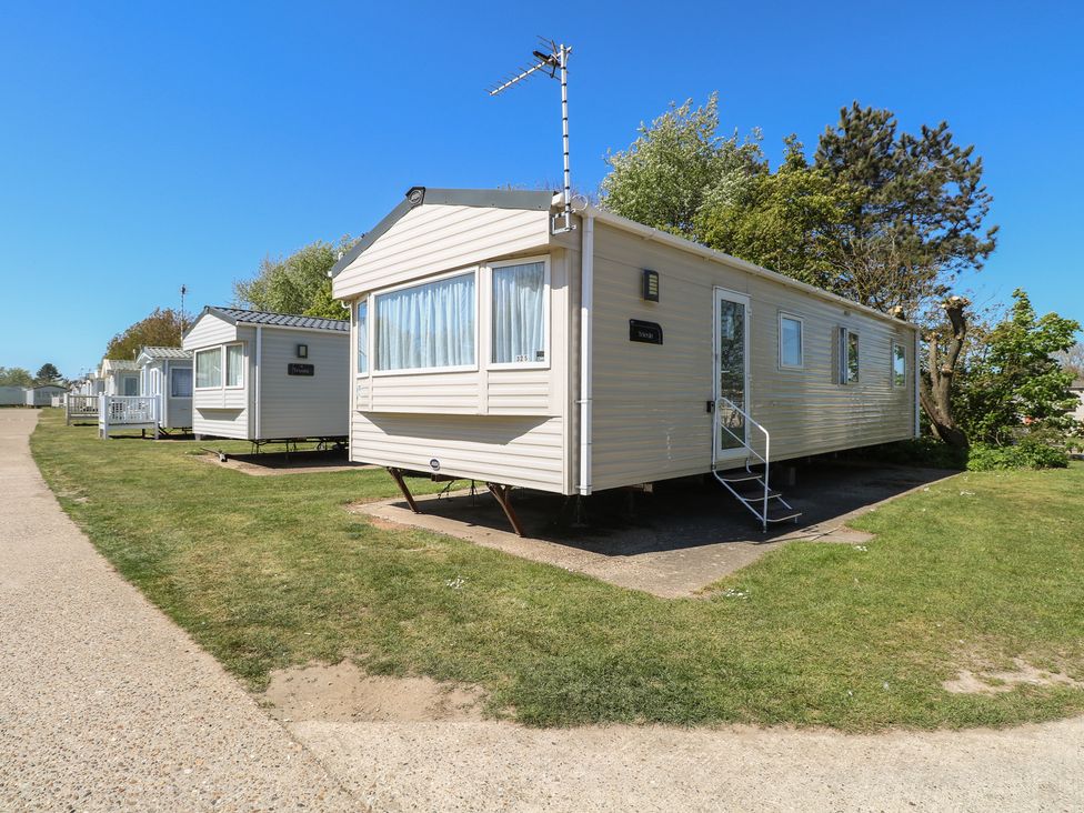 A caravan located on grass next to a pathway at Caravan 325 in Corton