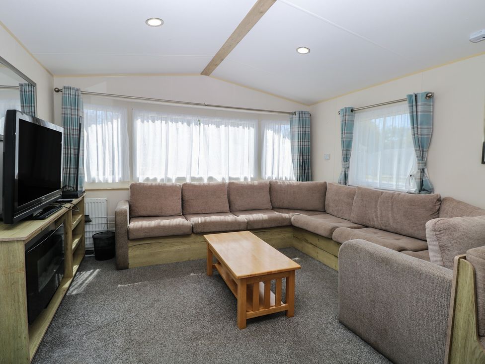 A living room with a corner sofa and television at Caravan 325 in Corton