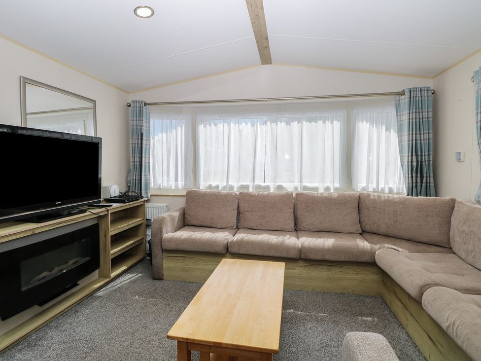A living room with a sofa and television at Caravan 325 in Corton