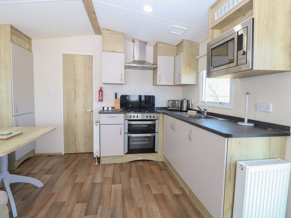 A kitchen with stove, microwave, sink, and folding table at Caravan 325 in Corton