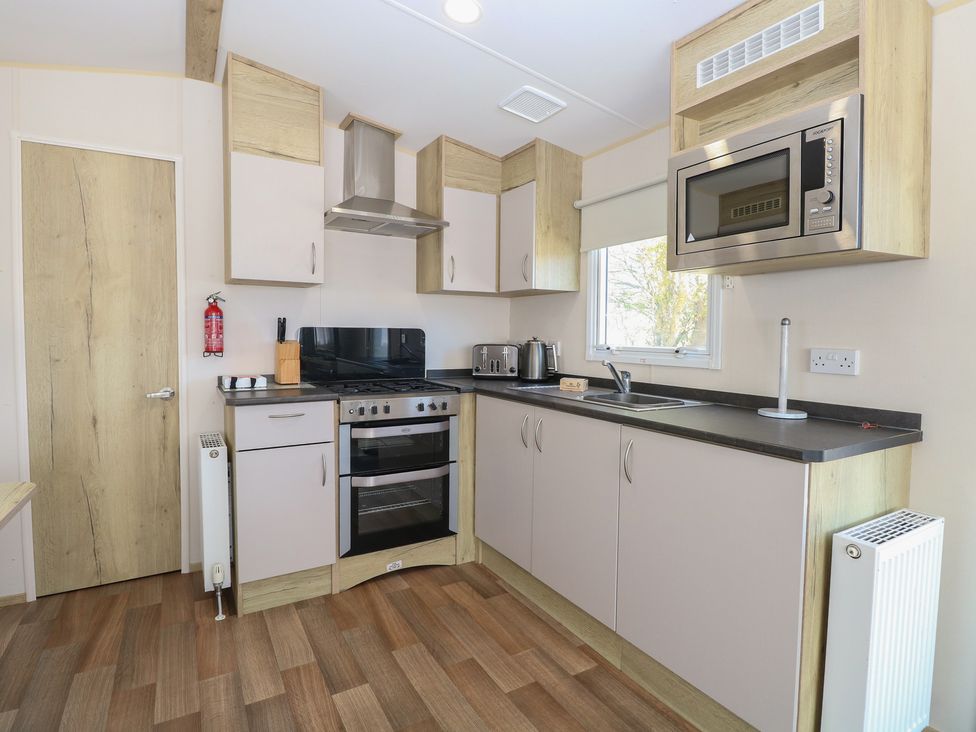 A kitchen with stove, oven, microwave and sink at Caravan 325 in Corton