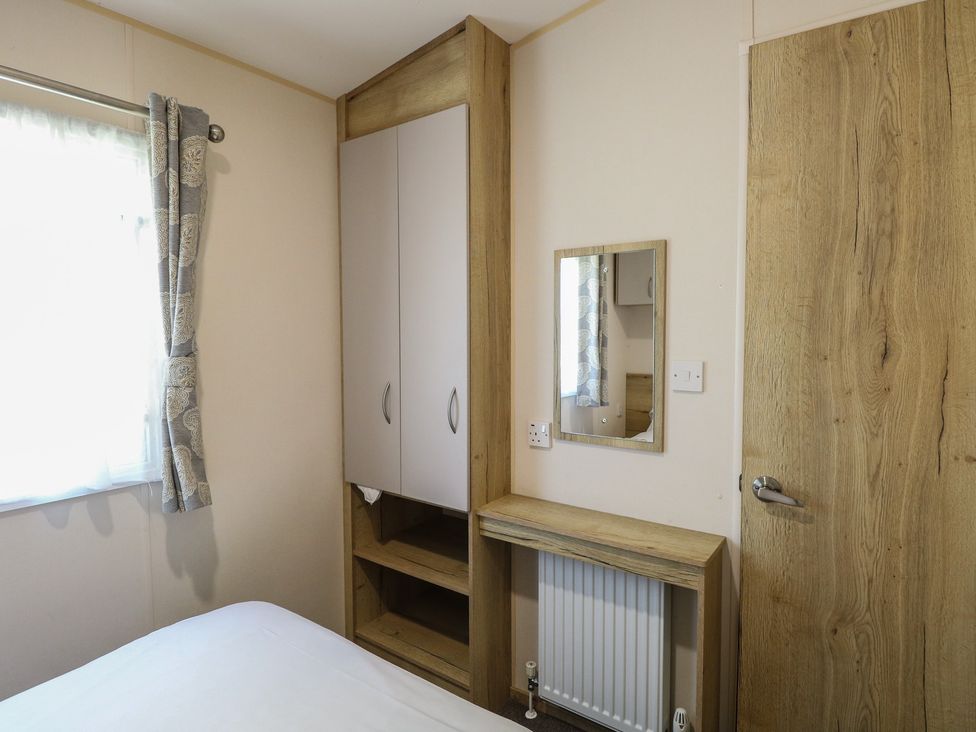 A bedroom with a wardrobe and mirror at Caravan 325 in Corton