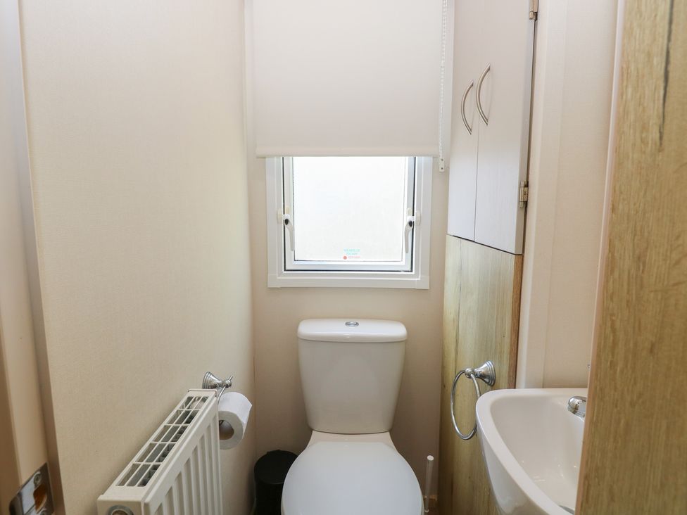 A bathroom featuring a toilet, sink, and cabinet at Caravan 325 in Corton