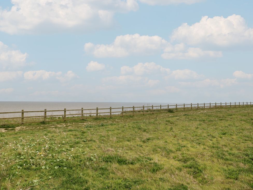 A view of a grass area with a fence overlooking the sea at Caravan 325 in Corton