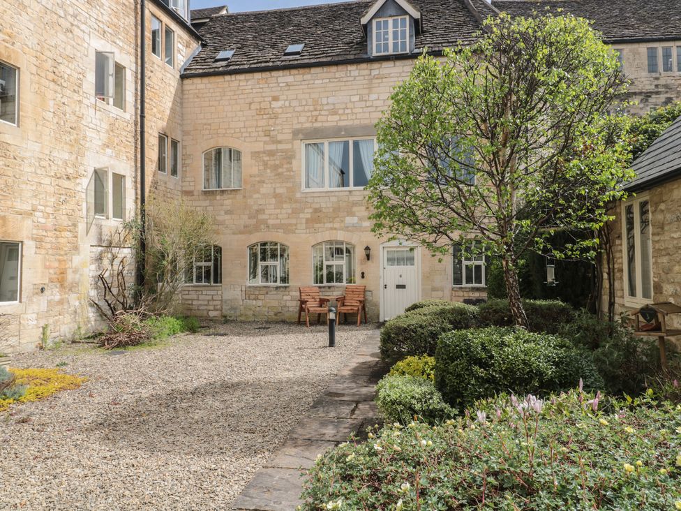 An outdoor area with stone walls and a bench at Longfords Mill near Nailsworth