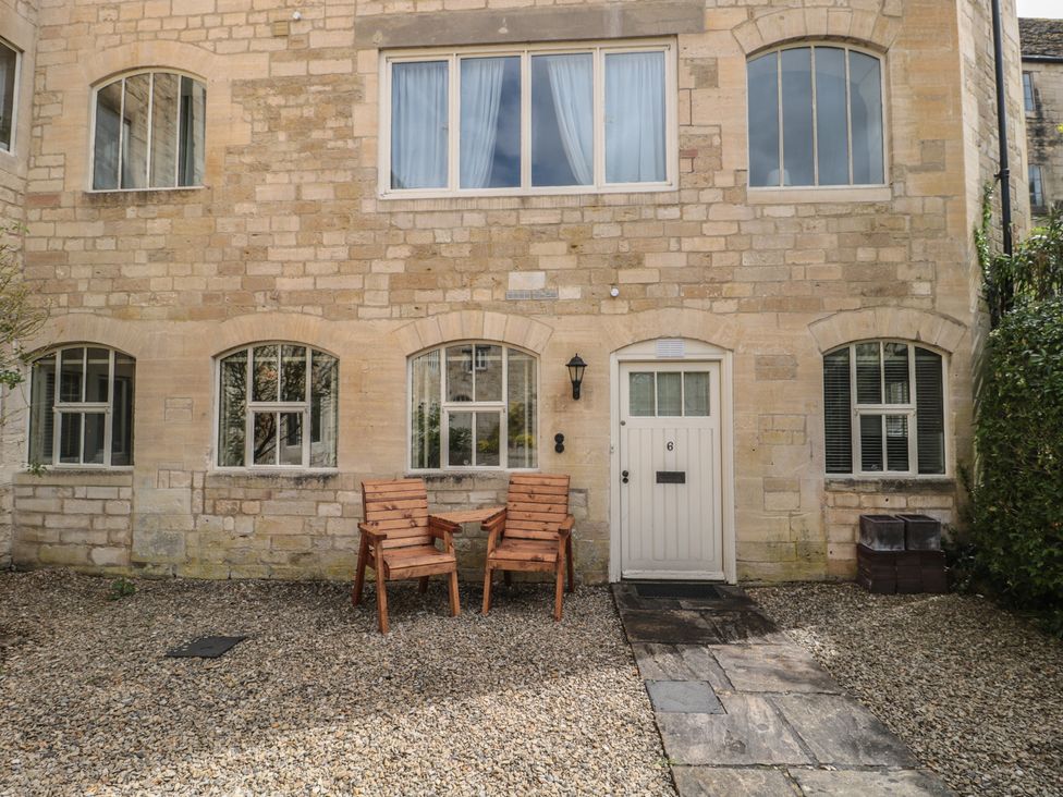 An exterior view of a building with two chairs and a door at Longfords Mill near Nailsworth