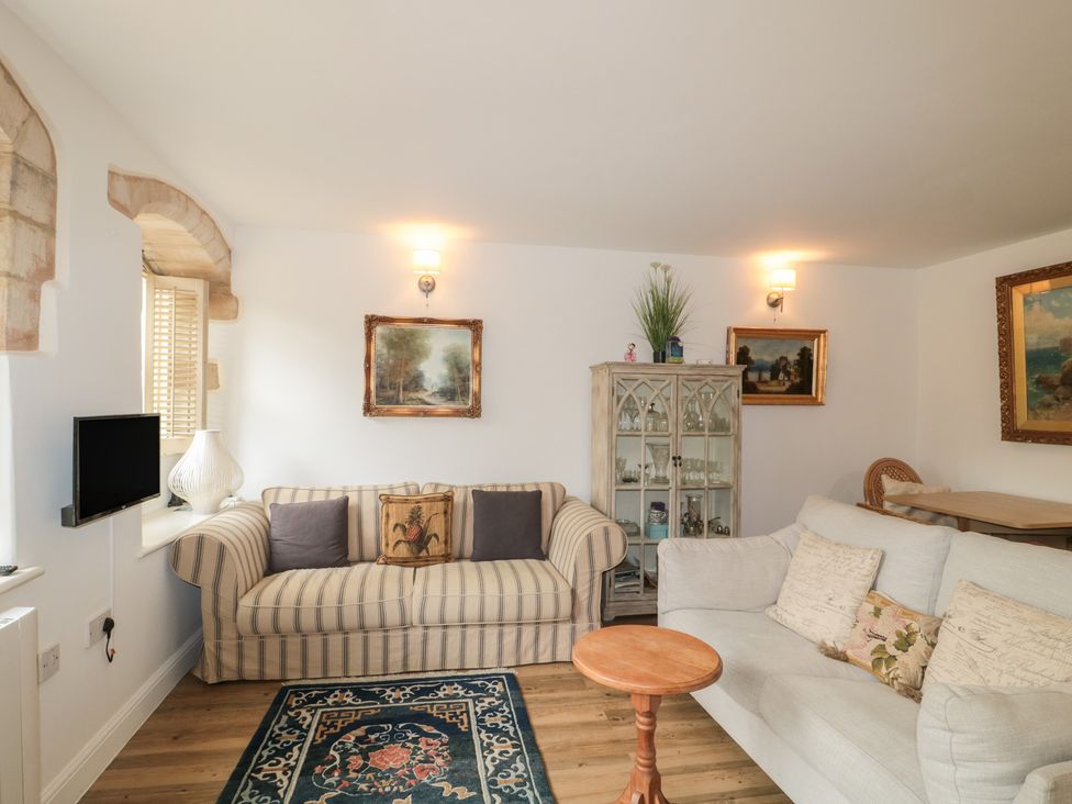 A living room with sofas, a coffee table, and a television at Longfords Mill near Nailsworth