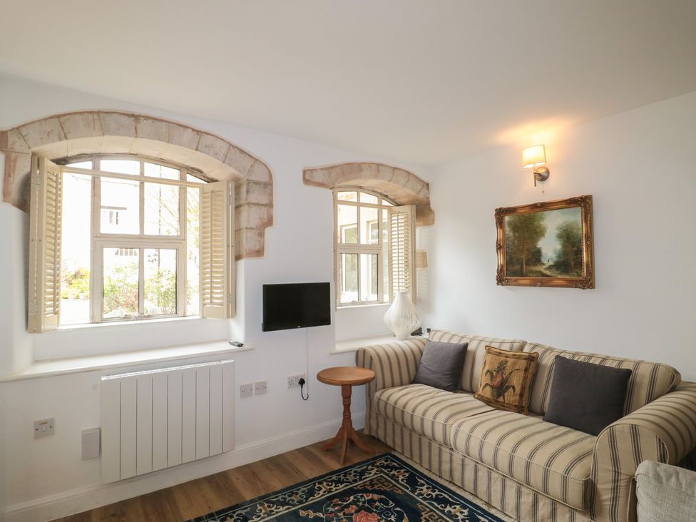 A living room with a sofa, table, and windows at Longfords Mill near Nailsworth