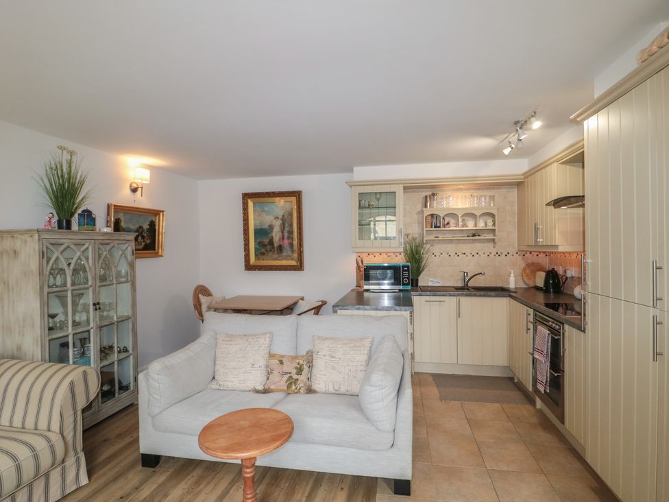 A living room with a sofa and kitchen appliances at Longfords Mill near Nailsworth