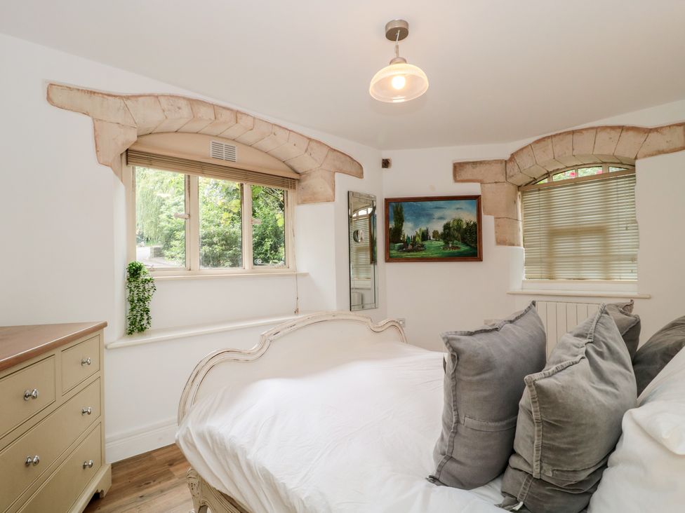 A bedroom with a bed and dresser at Longfords Mill, Minchinhampton