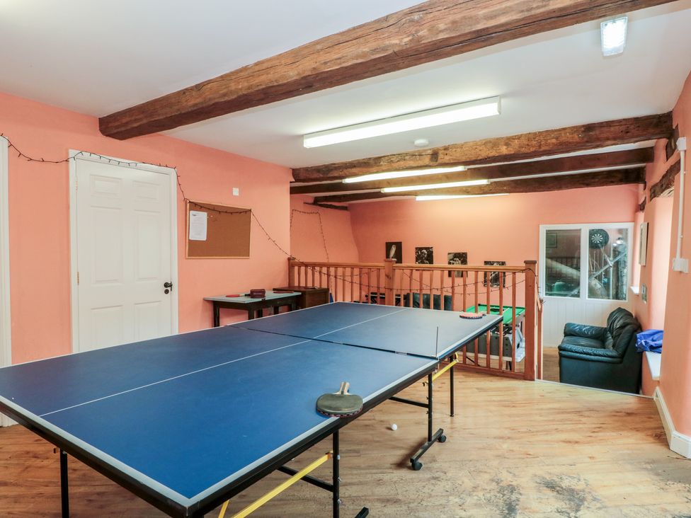 A game room with a table tennis table and a black couch at Longfords Mill, Minchinhampton
