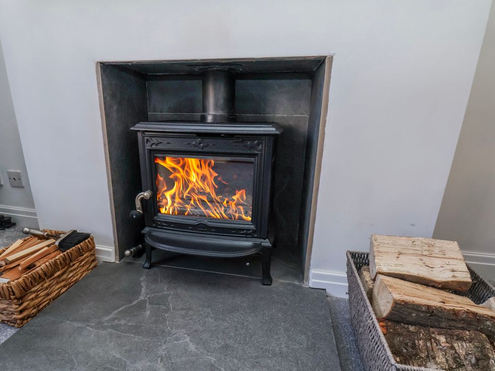 A wood stove with flames in a living room at 1 West Ville Mews York